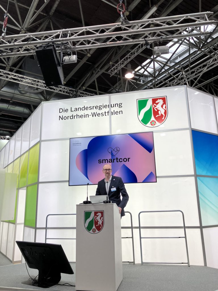 Dr. Christian Flottmann (novadocs GmbH) informiert über Wearables und digitale Prävention mit der smartcor App direkt vom Landesgemeinschaftsstand NRW auf der MEDICA 2023 in Düsseldorf.