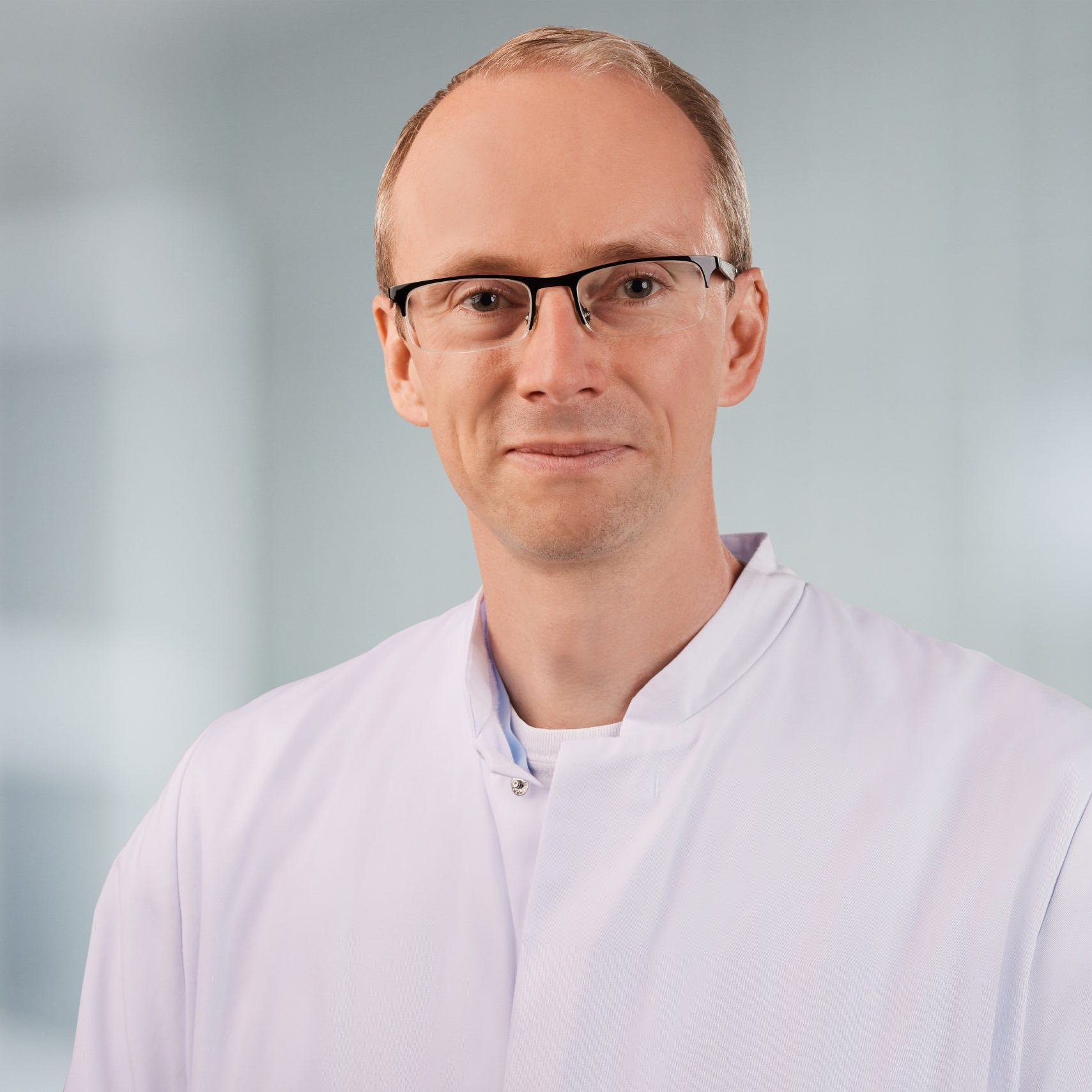 Dr._Christian_Flottmann_Profil Foto von Dr. med. Christian Flottmann, MHBA; sympathischer Mann mittleren Alters, mit kurzem, blondem Haar, Brille und Arztkittel