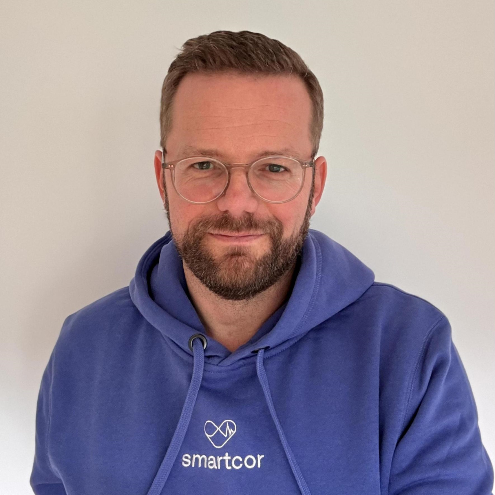 Foto von Stephan Garl; sympathischer Mann mittleren Alters, mit dunkelblondem, kurzem Haar, Brille und blauem smartcor-Hoodie
